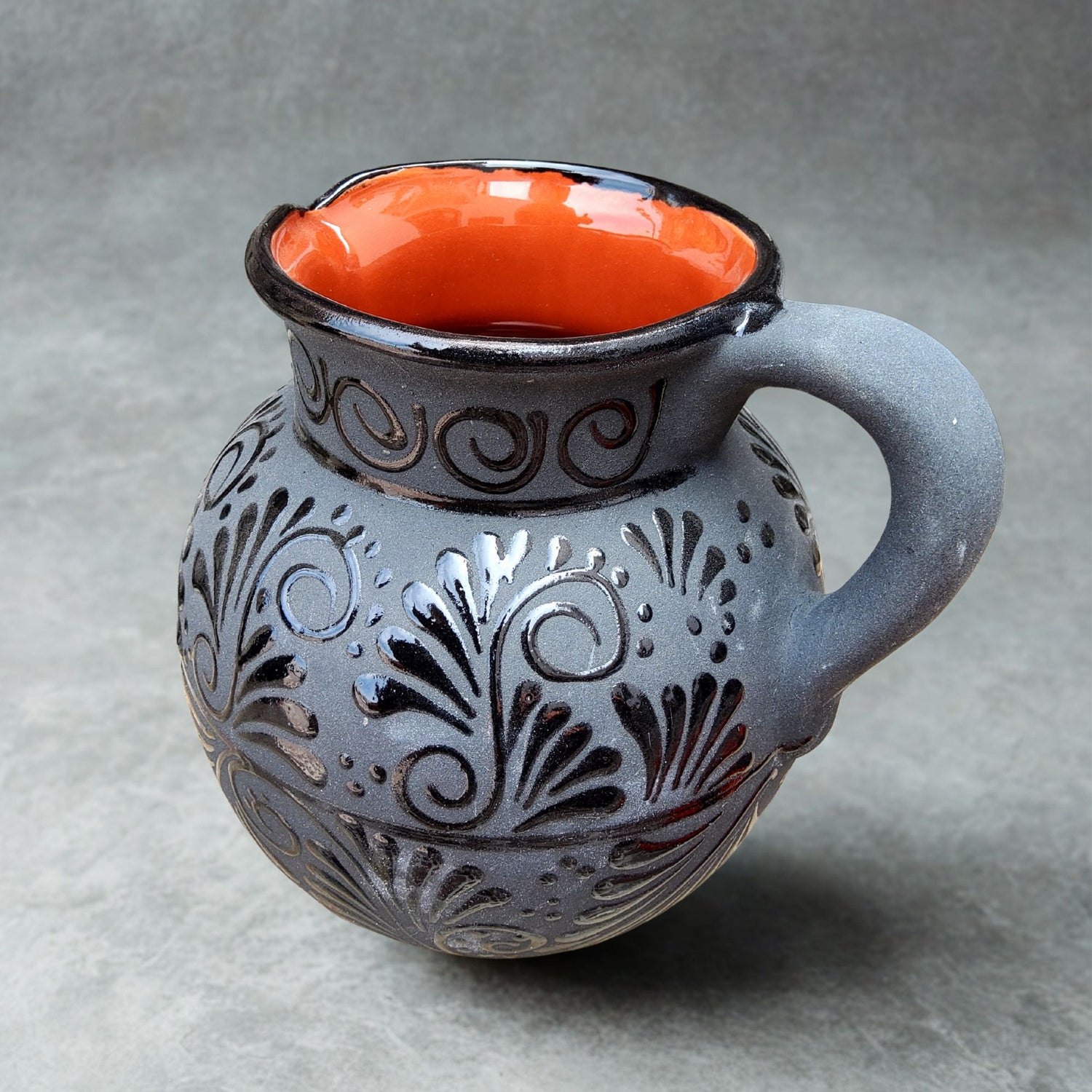 Decorative ceramic pitcher with floral patterns on a gray background