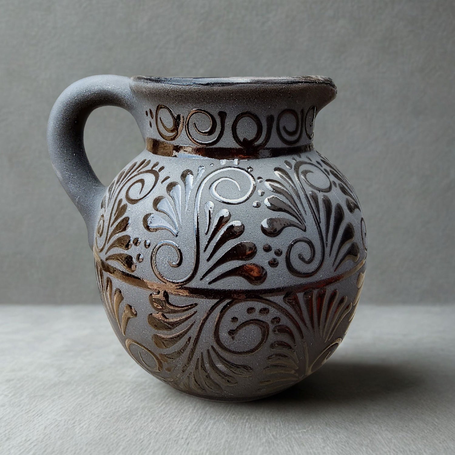 Decorative ceramic pitcher with intricate patterns on a gray background