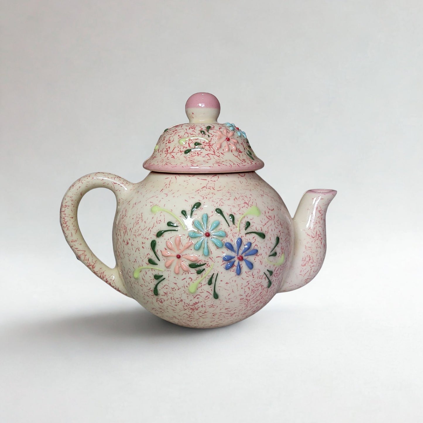 Ceramic teapot with floral designs on a white background