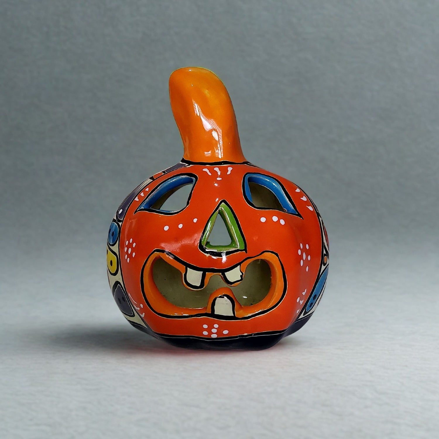 Ceramic pumpkin with a face on a gray background